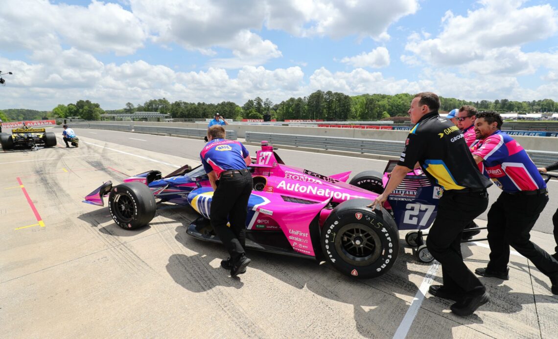 Alexander Rossi's car being pushed to pit lane by the rest of the Andretti Autosport crew