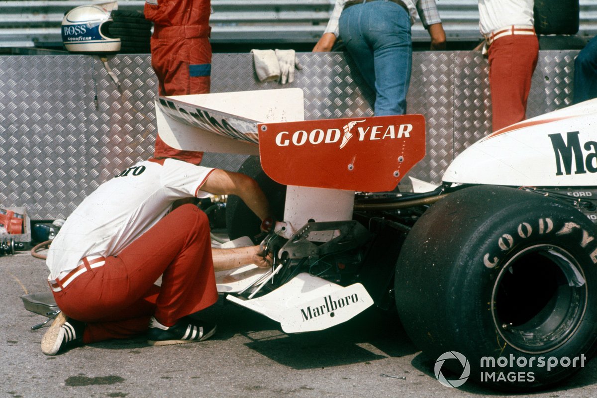 A mechanic works on the rear of the car of Jochen Mass, McLaren M23 Ford
