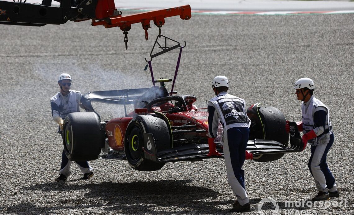Marshals remove the fire damaged car of Carlos Sainz, Ferrari F1-75, from the circuit
