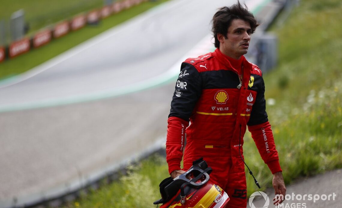 Carlos Sainz, Ferrari, walks away from his car after a fire