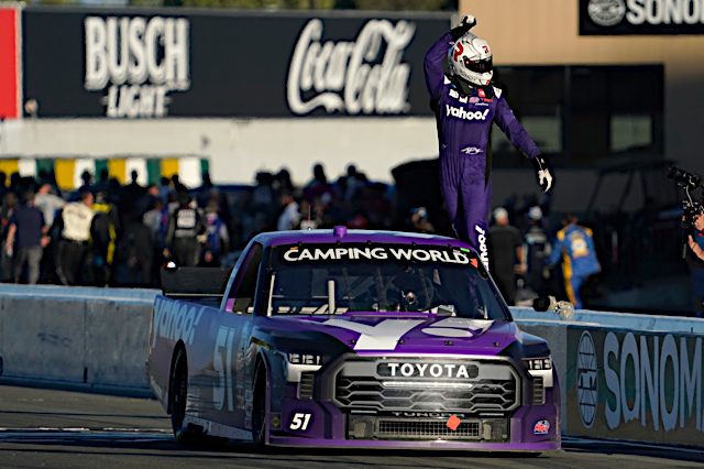 Kyle Busch celebrates winning Truck Series race at Sonoma Raceway, white helmet and purple firesuit and truck, NKP
