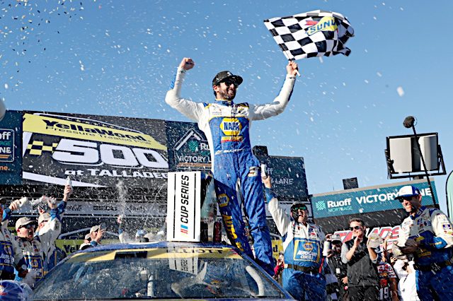 Chase Elliott celebrates in victory lane with checkered flag after winning at Talladega Superspeedway, NKP