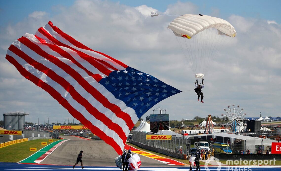 A parachutist arrives at the United States GP with a US flag