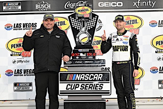 William Byron and Rudy Fugle hold up pointer fingers next to the Pennzoil 400 trophy at Las Vegas Motor Speedway, NKP