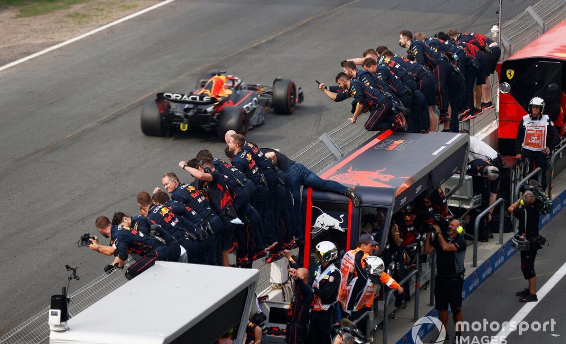 The team celebrate on the pit wall as Max Verstappen, Red Bull Racing RB18, crosses the line and takes the chequered flag