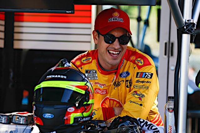 Joey Logano smiles with shades and a hat on, NKP