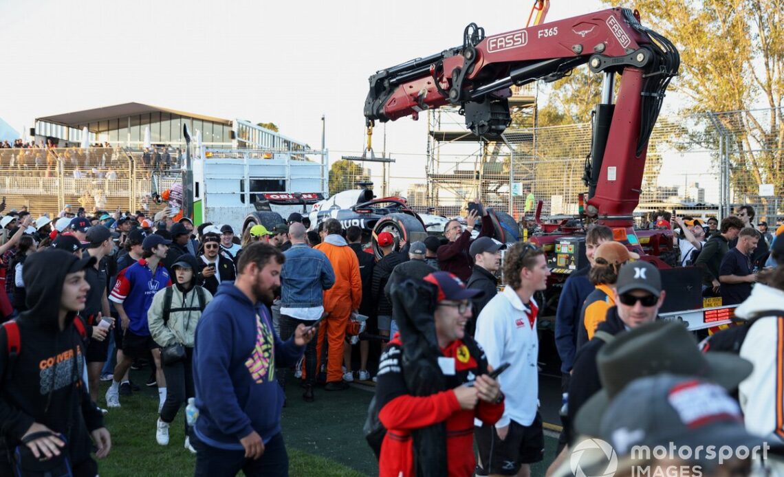 Fans invade the circuit as marshals load the car of Nyck de Vries, AlphaTauri AT04, onto a truck