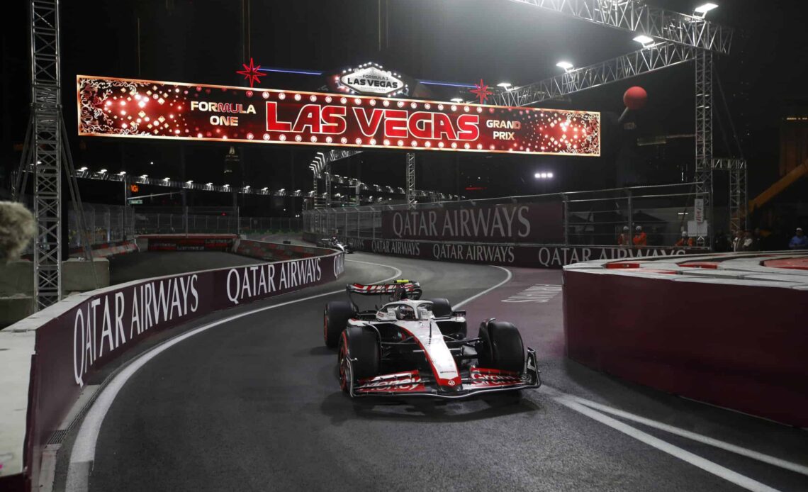 Nico Hulkenberg, No. 27 Haas VF-23, enters the pit lane during the 2023 Las Vegas Grand Prix, driving underneath a full-width monitor flashing "Las Vegas."