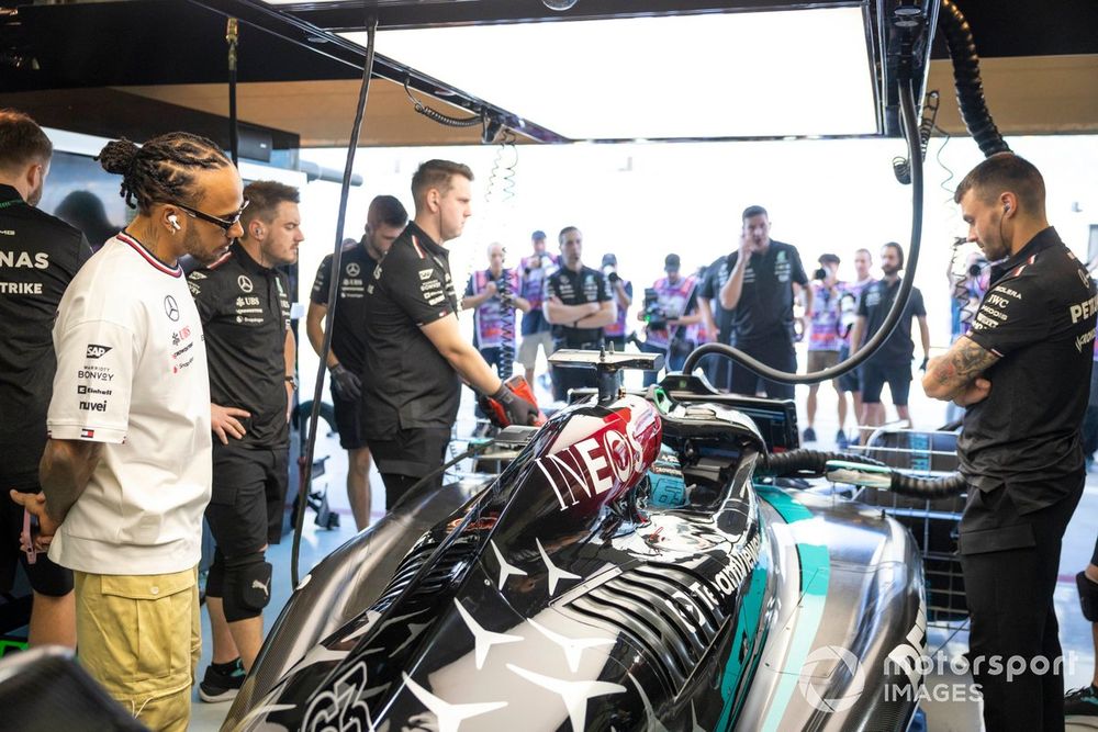 Lewis Hamilton, Mercedes-AMG, looks at the car of George Russell, Mercedes F1 W15, in the garage