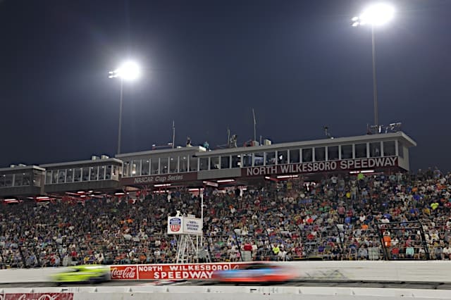NASCAR Cup Series cars of Ryan Blaney and Erik Jones in a blur racing on the Frontstretch at North Wilkesboro Speedway in the All-Star Race, fans in the stands, NKP