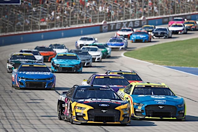 NASCAR Cup Series cars, led by Chase Briscoe and Ryan Blaney, race in a pack at Texas Motor Speedway, NKP