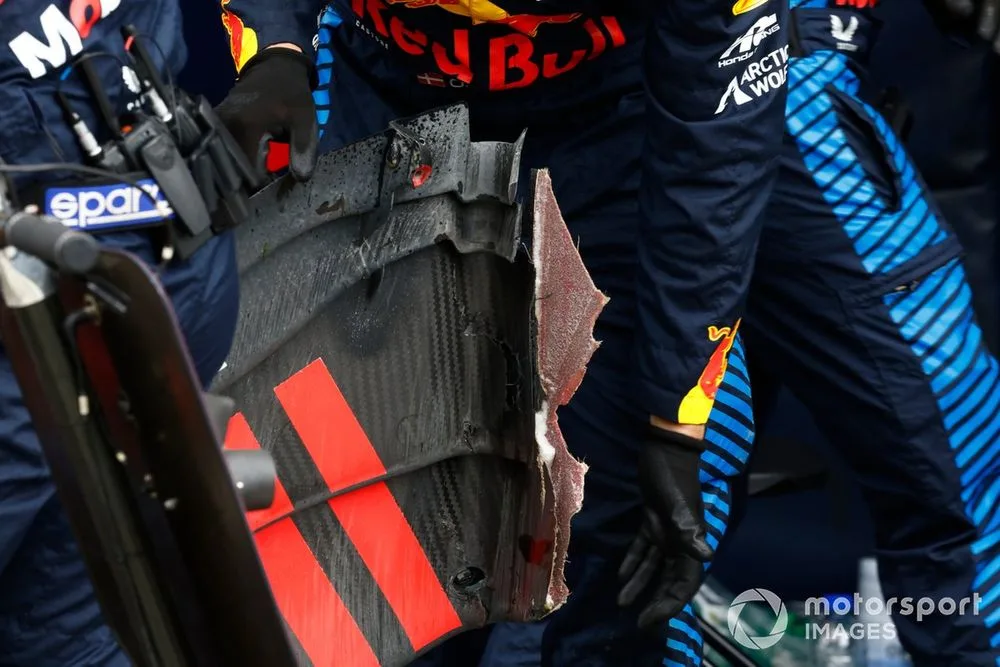 A Red Bull mechanic gathers the remains of the rear wing from the car of Sergio Perez, Red Bull Racing RB20
